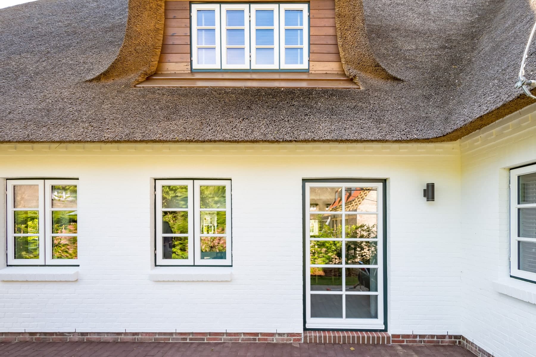 Weißes Reetdachhaus mit Holzfenstern